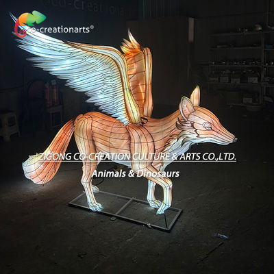 Огромная скульптура лисицы с сияющим фонарем, пернатые бирюзовые и белые крылья.